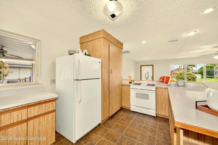 KITCHEN opens to living and dining areas. Looks out to covered lanai and spacious backyard. IMAGINE THE POTENTIAL!