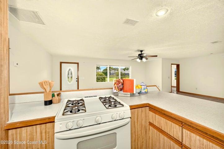 KITCHEN opens to living and dining areas. Looks out to covered lanai and spacious backyard. IMAGINE THE POTENTIAL!