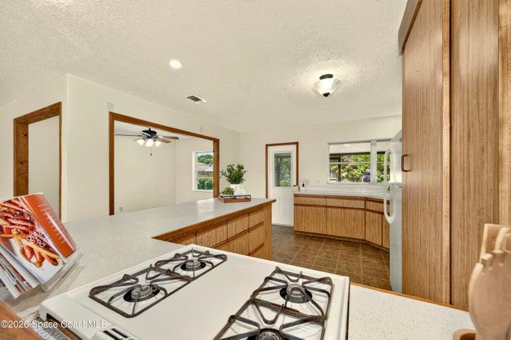 KITCHEN opens to living and dining areas. Looks out to covered lanai and spacious backyard. IMAGINE THE POTENTIAL!