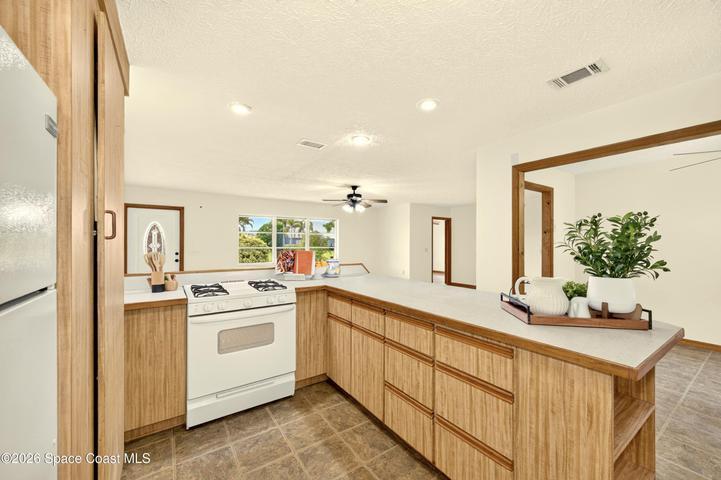 KITCHEN opens to living and dining areas. Looks out to covered lanai and spacious backyard. IMAGINE THE POTENTIAL!