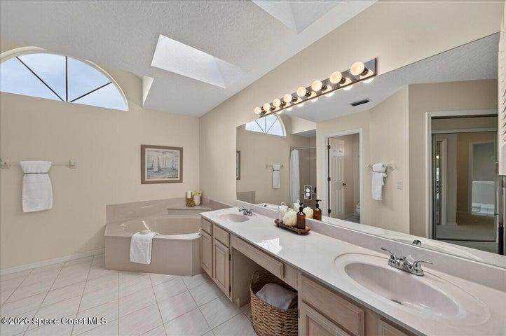 En suite bathroom with a double sink vanity, soaking tub and Shower that is out of view on the left.