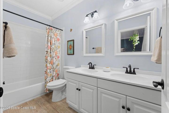 Bright primary bathroom featuring a spacious dual-sink vanity, updated finishes and a tub/shower combination.