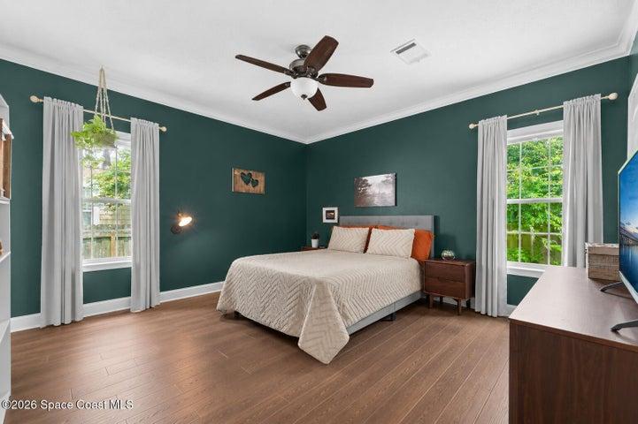 Spacious primary bedroom featuring abundant natural light, new warm wood-look vinyl flooring and plenty of room to create a relaxing retreat.