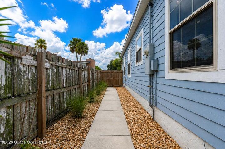 Side view of the home featuring a convenient walkway accented by newly placed coquina rock for a clean, low-maintenance finish.