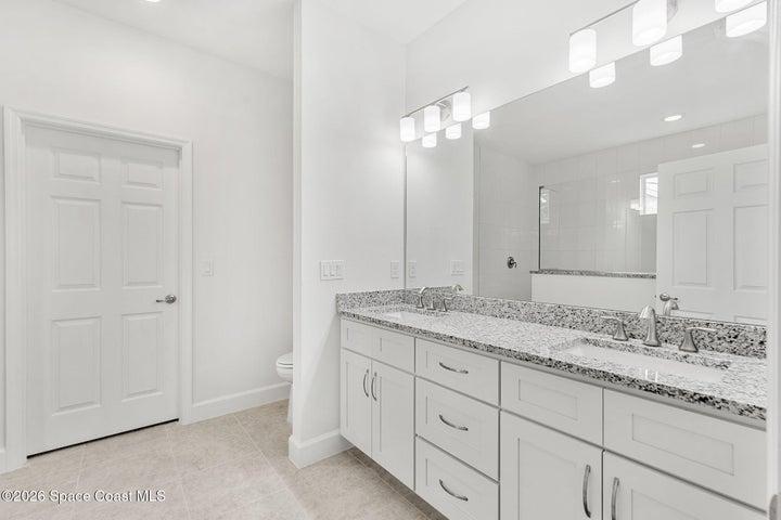 Dual sinks with granite countertops, and crisp white cabinets.
