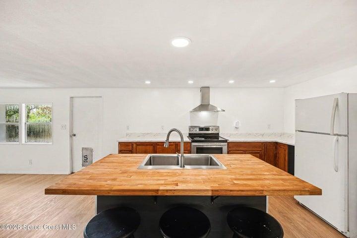 Kitchen Island Featuring Storage, Sink, Wood Countertop, and Seating