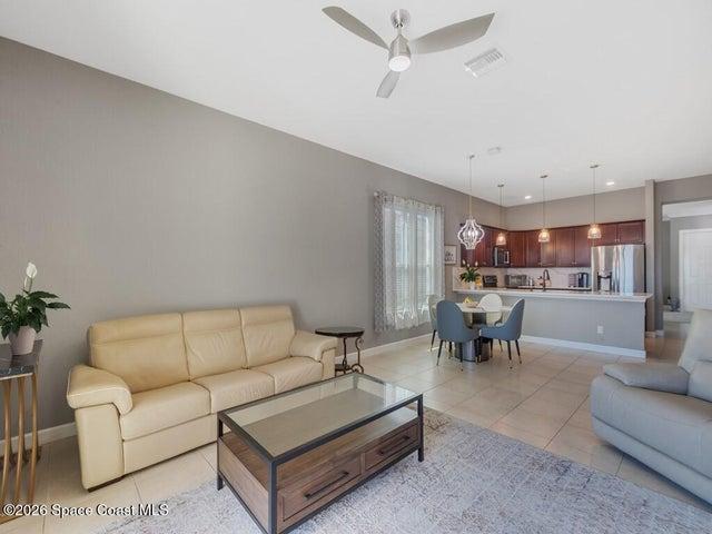 Open-concept living space featuring neutral-toned walls, tile flooring, and a ceiling fan with integrated lighting