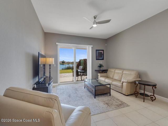 Living area featuring tile flooring, a ceiling fan, and sliding glass doors opening to a patio