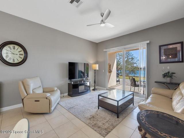 Spacious living area featuring tile flooring, a modern ceiling fan, and sliding glass doors opening to an outdoor patio