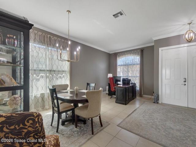 Interior space featuring tile flooring, neutral wall paint, and crown molding