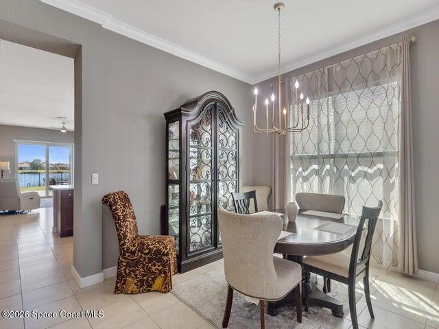 Dining area featuring a modern chandelier, crown molding, and large window with decorative sheers