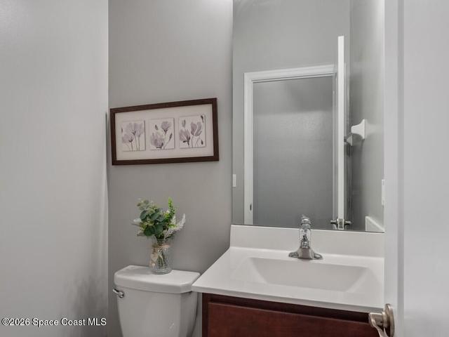 Powder room featuring a single vanity with a white countertop and wood-finish cabinetry