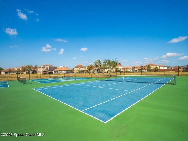 Multi-court facility featuring blue and green hard courts, white court lines, and black chain-link fencing