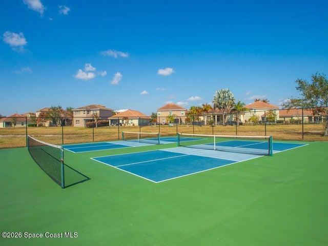 Multi-court facility featuring blue and green hard courts, white court lines, and black chain-link fencing