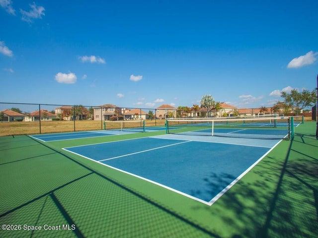 Multi-court facility featuring blue and green hard courts, white court lines, and black chain-link fencing