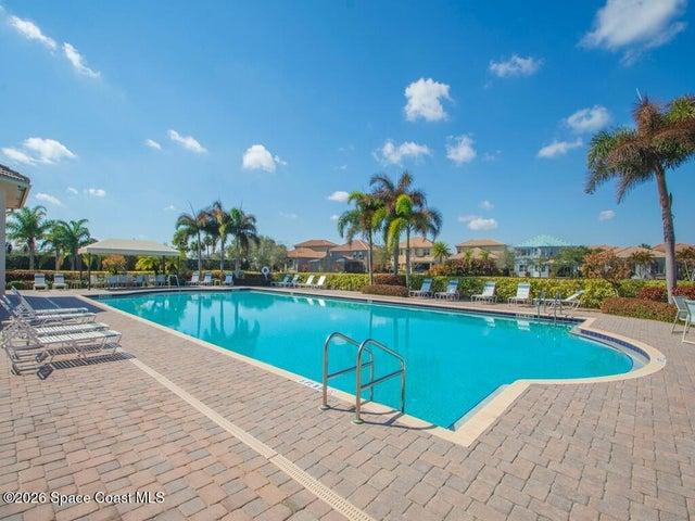 Outdoor swimming pool with integrated steps, surrounded by a brick paver deck and mature landscaping