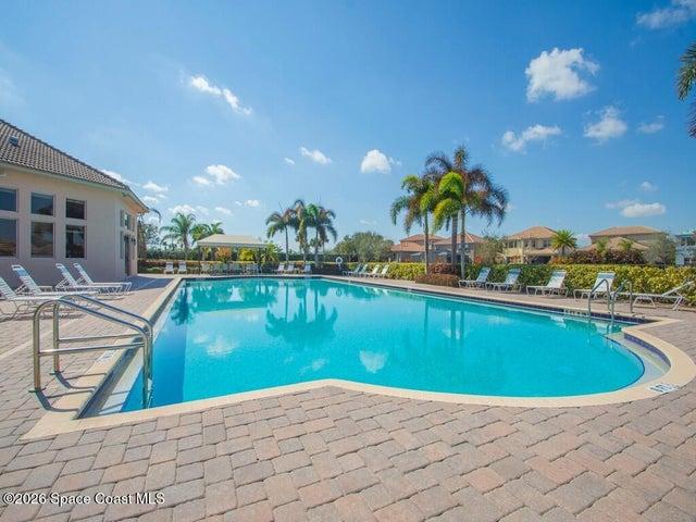 Outdoor swimming pool with integrated steps, surrounded by a brick paver deck and mature landscaping