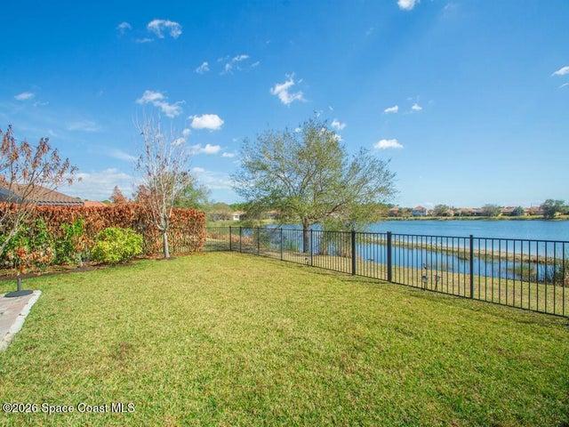 Expansive waterside grounds featuring a mature tree, natural shoreline, and distant residential structures