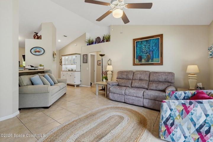 Vaulted ceiling with an overhead fan light fixture, tile flooring, and a built-in display cabinet