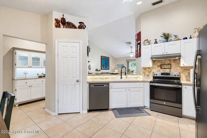 Kitchen featuring white cabinetry, light countertops, stainless steel appliances, and a tile backsplash