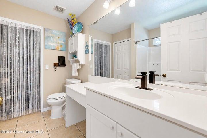 Vanity with an integrated sink and bronze-finish faucet, an expansive mirror, and tile flooring