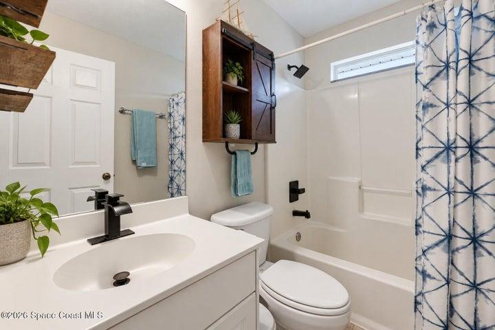 White vanity with integrated sink, matte black faucet, and rectangular mirror