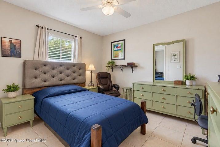 Tile flooring, window with blinds, ceiling fan, and built-in wall shelving