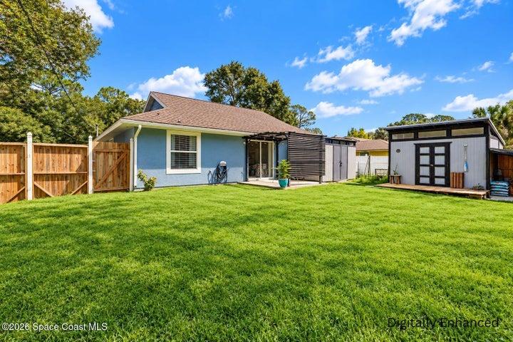 Expansive backyard with a lush lawn, privacy fencing, and two detached storage structures