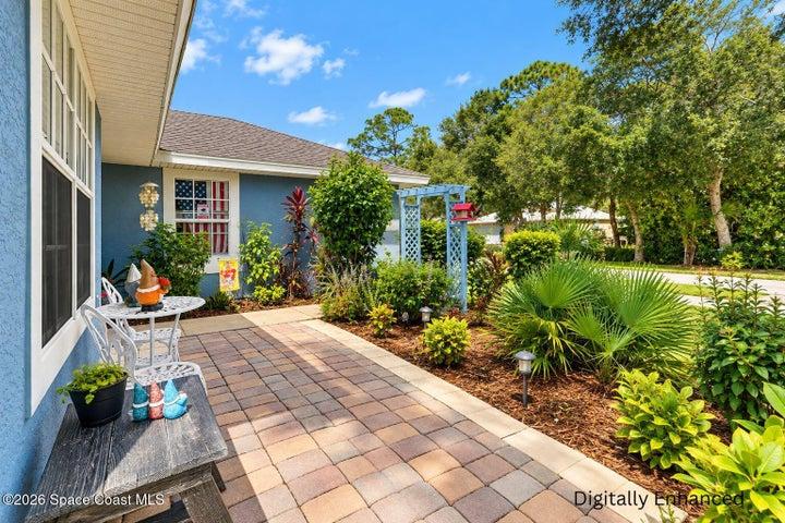 Front exterior featuring a red entry door, shingled roof, light blue siding, and a paver patio