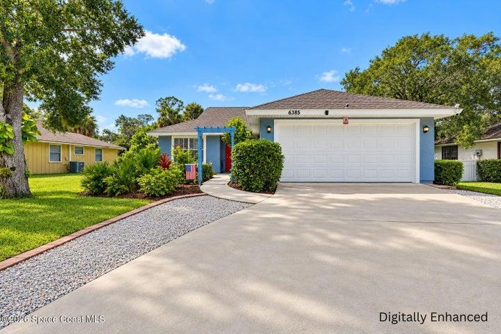 Front exterior with a two-car garage, mature landscaping, a paved driveway, and a gravel walkway