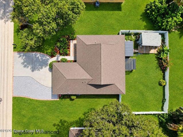 Expansive fenced backyard featuring a detached accessory structure, mature landscaping, and covered patio area