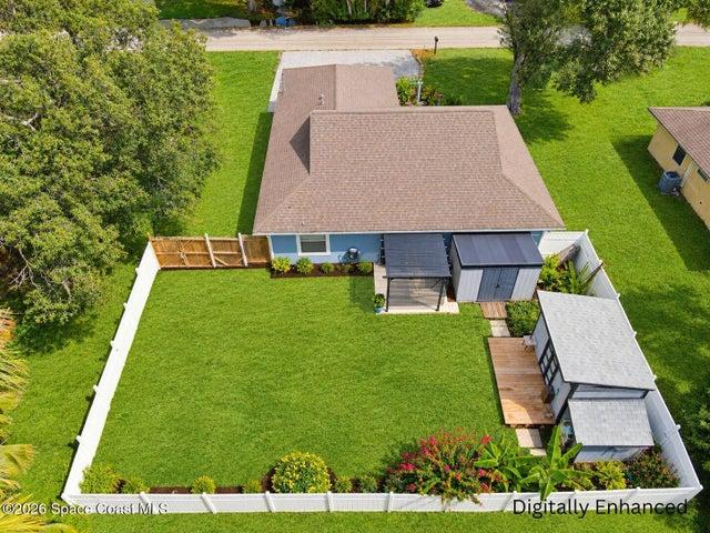 Expansive fenced backyard featuring a detached accessory structure, mature landscaping, and covered patio area