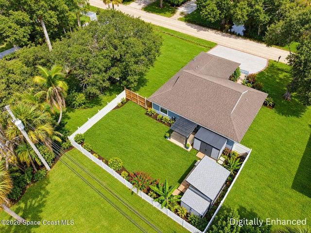 Expansive fenced backyard featuring a detached accessory structure, mature landscaping, and covered patio area