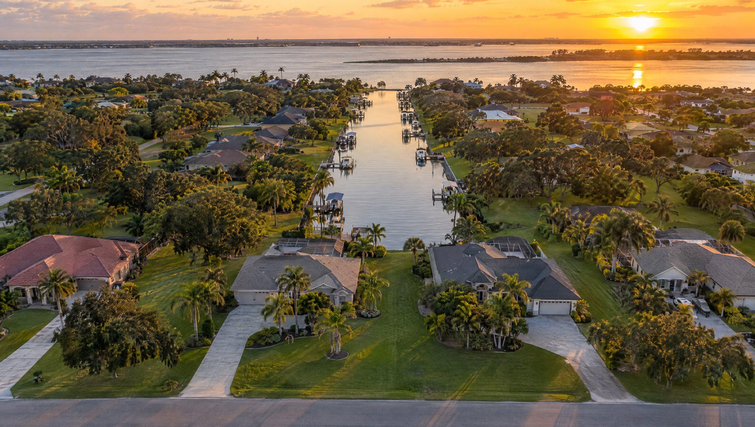 Aerial view at golden hour of an inland Space Coast neighborhood of homes on large lots along a residential canal leading to the Indian River lagoon