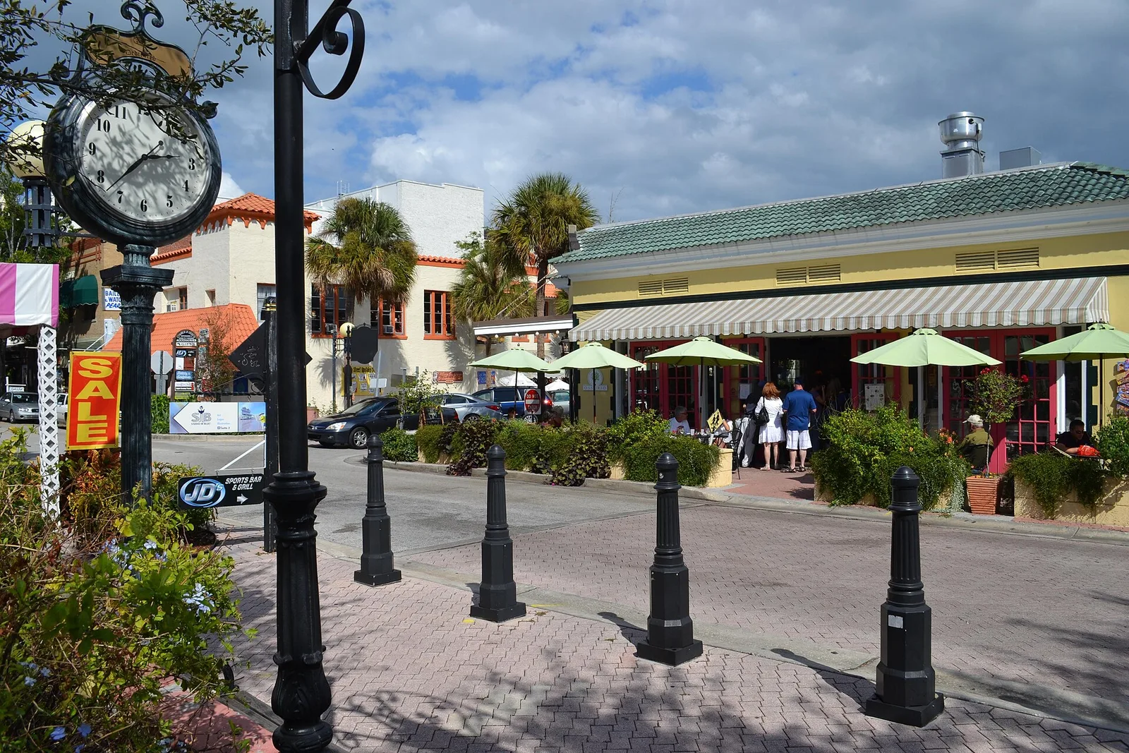 A shaded street of shops and café umbrellas in Historic Cocoa Village